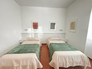3 camas en una habitación con paredes blancas en La Nuova Dimora B&B, en LʼAquila