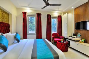 a bedroom with a bed and a tv and red curtains at Hotel Delhi Fab - Near Connaught Palace in New Delhi