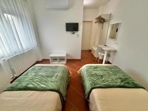 two beds in a room with a television and a desk at La Nuova Dimora B&B in LʼAquila