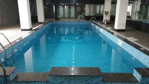 a large swimming pool with blue water in a building at Javson Airport Hotel in Sialkot