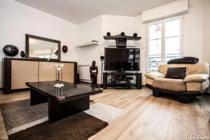 a living room with a couch and a table and a television at Chic apart with parking near Paris in Colombes