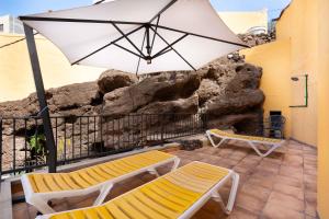 eine Terrasse mit zwei Bänken und einem Sonnenschirm in der Unterkunft Las Fajanas de Gáldar in Las Palmas de Gran Canaria