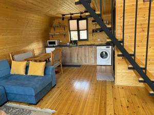 a living room with a blue couch and a kitchen at Qusha Cottage in Kazbegi