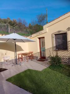 un patio con mesa y sombrilla en New! La Ginestra,casa vacanze in montagna-Seulo Sardegna, en Seùlo