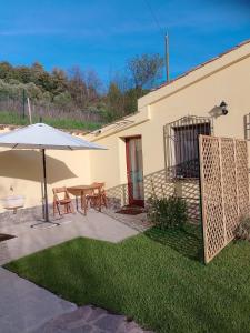 un patio con sombrilla, mesa y sillas en New! La Ginestra,casa vacanze in montagna-Seulo Sardegna, en Seùlo