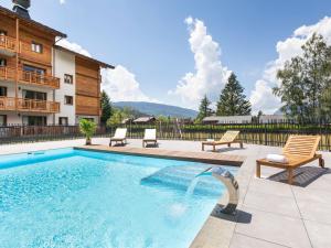 a swimming pool with two chairs and a building at Beautiful residence with Spa in cozy Samo ns in Samoëns