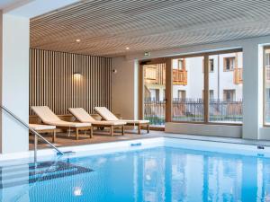 a swimming pool with lounge chairs next to a building at Beautiful residence with Spa in cozy Samo ns in Samoëns