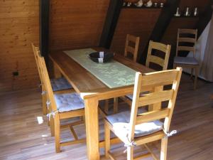 a wooden table and chairs with a table and a bowl on it at Wooden bungalow with a terrace in a wooded area in Berneburg