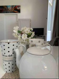 沙特爾的住宿－Studio Rdc Chartres gare et Colisée a 100m，两个白茶壶和一个花瓶,桌子上放着鲜花