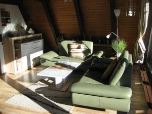 a living room with two green couches and a table at Wooden bungalow with a terrace in a wooded area in Berneburg