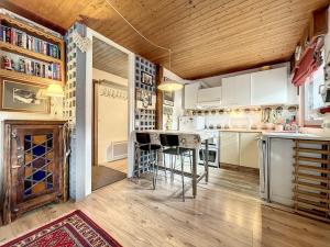 a kitchen with white cabinets and a bar with stools at Pied de ladroit - appartement - 4 pers - centre in Les Gets