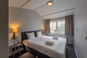 a bedroom with a bed with white sheets and a window at Zeayou Zeeland - Appartementen Beatrixstraat 29 in Domburg