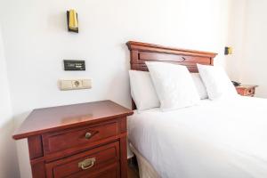 a bedroom with a bed and a nightstand with white sheets at Hostal La Muralla in Zahara de los Atunes