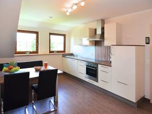 eine Küche mit einem Tisch und einem weißen Kühlschrank in der Unterkunft Modern Apartment in Eslarn with Lake Near in Eslarn