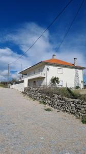 a white house with a stone wall in front of it at Villa Mendes Oliva in Almeida