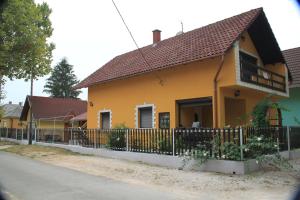 a yellow house with a fence in front of it at Kovács vendégház in Harkány