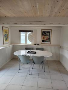une salle à manger avec une table et des chaises blanches dans l'établissement Ragnhilds Gård, Hostel, à Nyord