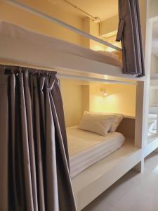Ce lit se trouve dans un dortoir doté de lits superposés et d'un rideau. dans l'établissement Line Bangkok Hostel, à Bangkok