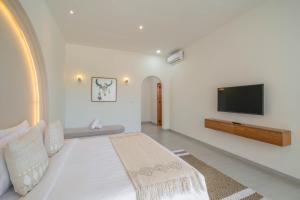 a white room with a bed and a flat screen tv at Villa Yuri - Stylish and Tropical Oasis 2BR Villa in Canggu in Canggu