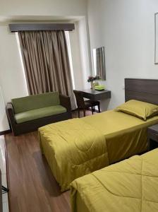 a hotel room with two beds and a chair and a table at Bayou Bliss@Bayou Lagoon in Ayer Keroh