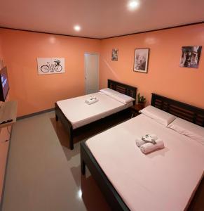 2 Betten in einem Zimmer mit orangefarbenen Wänden in der Unterkunft Halajo bnb transient in Laoag