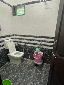 a bathroom with a toilet and a bucket at Tuljai Homestay in Tuljapur