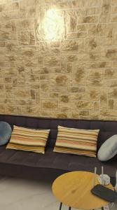 Sofá negro con almohadas y pared de ladrillo en Villa Marina ixia, Rodos, en Ixia