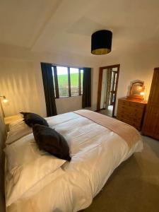een slaapkamer met een wit bed met 2 kussens erop bij The Linhay at Hewish Mill in Barnstaple