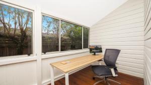 a home office with a desk and two windows at Family Retreat Woy Woy in Woy Woy