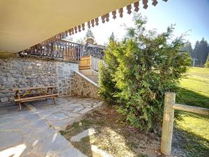 un patio con un banco de madera y una pared de piedra en Grizzli 23 - appartement - 4 pers - Ski-in-out, en Les Gets