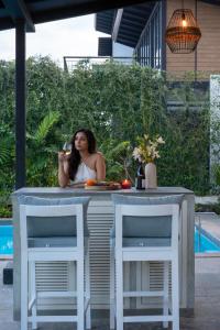 a woman sitting at a table with a glass of wine at LohonoStays Villa Siena D in Alibaug