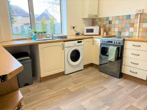 a kitchen with a washing machine and a microwave at Charming 3-bed Home In Bourne in Lincolnshire