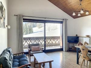 a living room with a couch and a large sliding glass door at Cornuts 2 - appartement -5pers in Les Gets