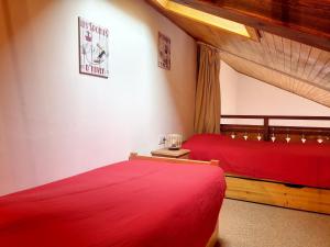 two beds in a room with red sheets at Cornuts 2 - appartement -5pers in Les Gets