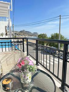 un balcone con tavolo e fiori su una ringhiera di Orfeas Sea View House a Archangelos