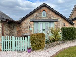 ein Backsteinhaus mit grüner Tür und einem Zaun in der Unterkunft Jasmine Cottage in Paignton