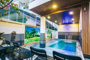 a pool in a building with chairs and a table at Villa FLC Sầm Sơn - Sao biển 98 in Sầm Sơn