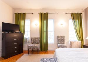 a bedroom with green curtains and a bed and a television at Gorgeous Apt for 2! Heart of Manhattan! in New York