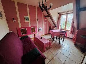 ein Wohnzimmer mit einem rosa Sofa und einem Tisch in der Unterkunft LOCATION à COUCY LE CHATEAU in Coucy-le-Château-Auffrique