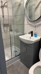 La salle de bains est pourvue d'une douche, d'un lavabo et d'un miroir. dans l'établissement Acton high street, à Londres