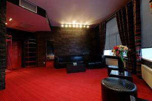 トムスクにあるHotel Toyanの赤いカーペットフロアのリビングルーム(黒い革の家具付)