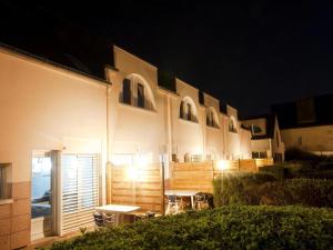 un edificio iluminado con mesas y sillas por la noche en Holiday resort Golfe du Morbihan Larmor Baden acc for 4 pers, en Larmor-Baden