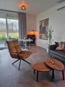 ein Wohnzimmer mit einem Sofa, einem Stuhl und einem Tisch in der Unterkunft Bembom Hoeve Guesthouse in Lutten