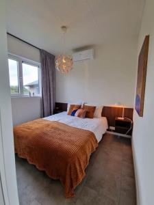 ein Schlafzimmer mit einem großen Bett mit einer orangefarbenen Decke in der Unterkunft Bembom Hoeve Guesthouse in Lutten