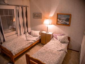 two beds in a room with a lamp and a window at Kiinteistö Hetekka in Kouvola