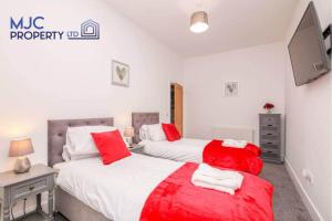 two beds in a bedroom with red and white sheets at Mansfield in Hawick