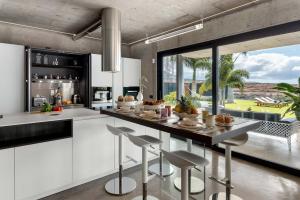 a kitchen with white cabinets and a counter with stools at Karat Atelier de la vega in Playa Paraiso