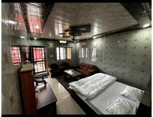 a bedroom with a bed and a couch in a room at Anu Shree Lodge, Ukhimath in Ukhimath