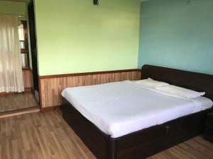 uma cama com lençóis brancos e almofadas num quarto em Hotel Mandala em Kathmandu