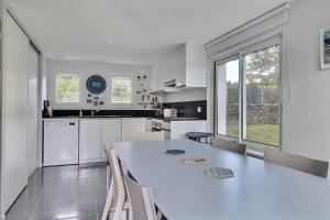 eine weiße Küche mit einem großen weißen Tisch und Stühlen in der Unterkunft le toul braz in Saint-Gildas-de-Rhuys + 19 Fotos